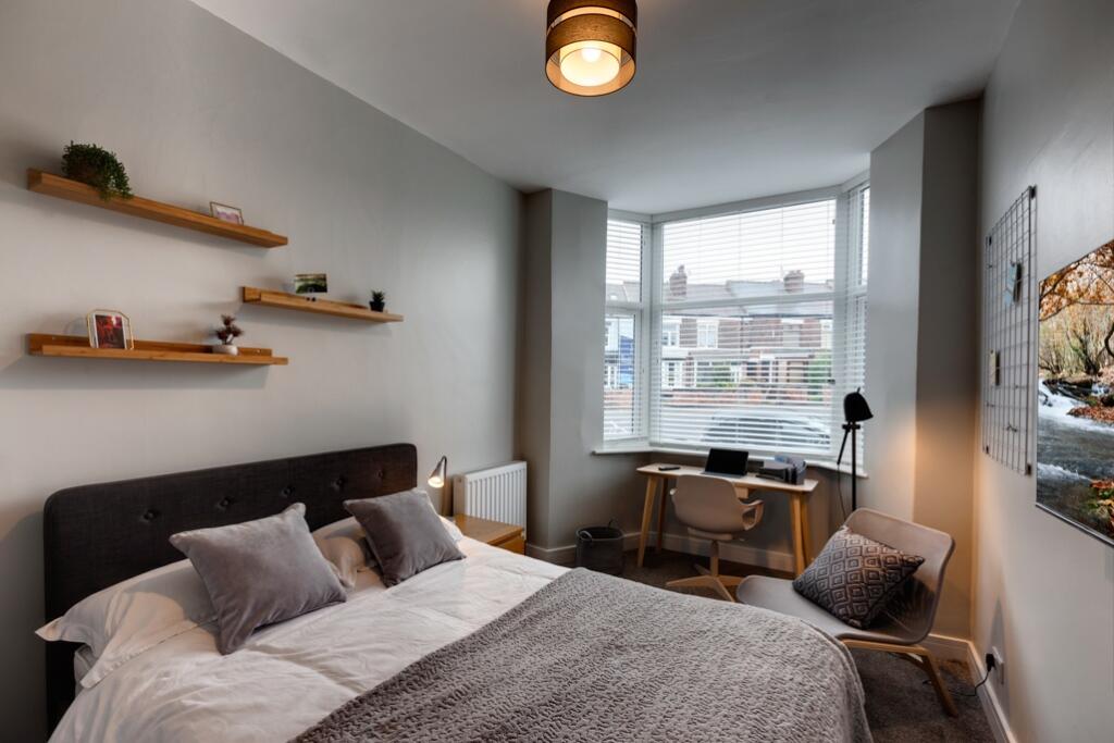 A cozy, well-lit bedroom featuring a comfortabl...