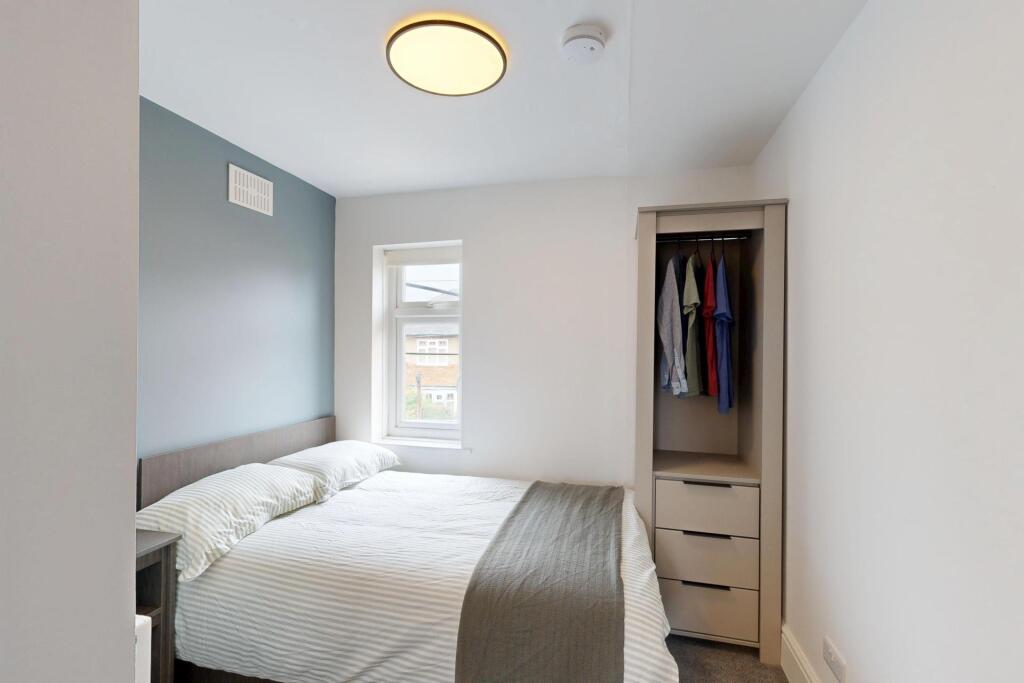 A well-lit, tidy double bedroom featuring a com...