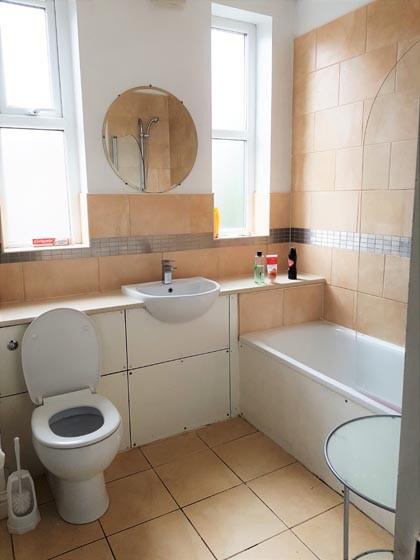 A clean, well-lit bathroom featuring a bathtub,...