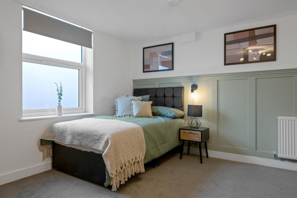 A spacious and well-lit bedroom featuring a lar...