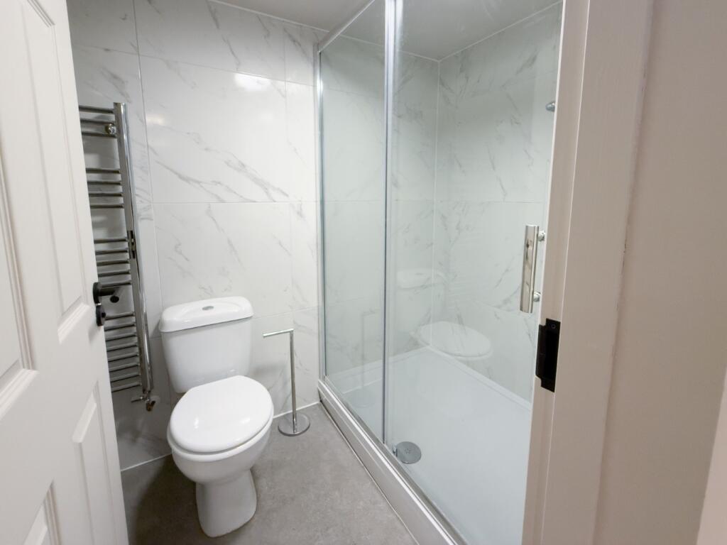 Bright, modern bathroom with a large glass-encl...