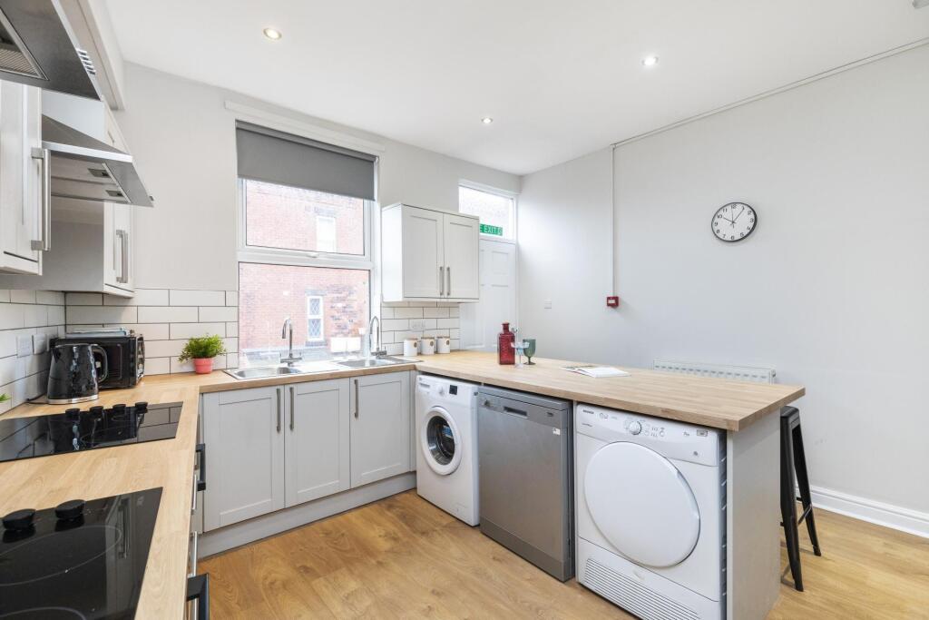 Bright, modern kitchen with light wood countert...