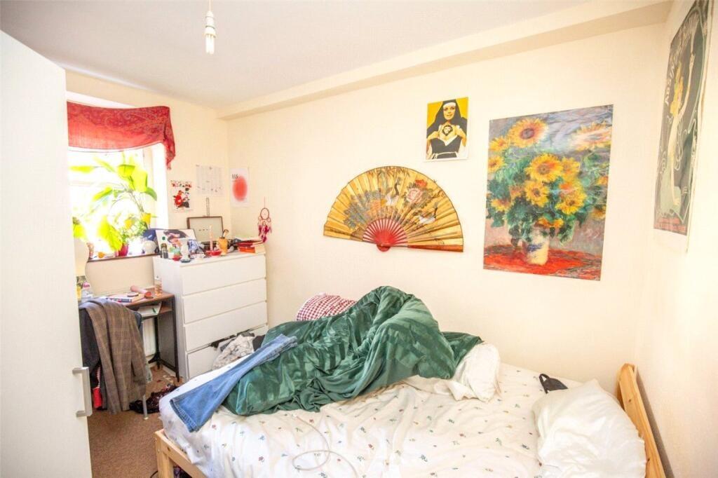 A cozy bedroom featuring a bed with green beddi...
