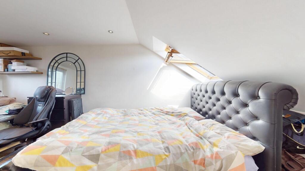 A spacious and cozy attic bedroom with a large ...