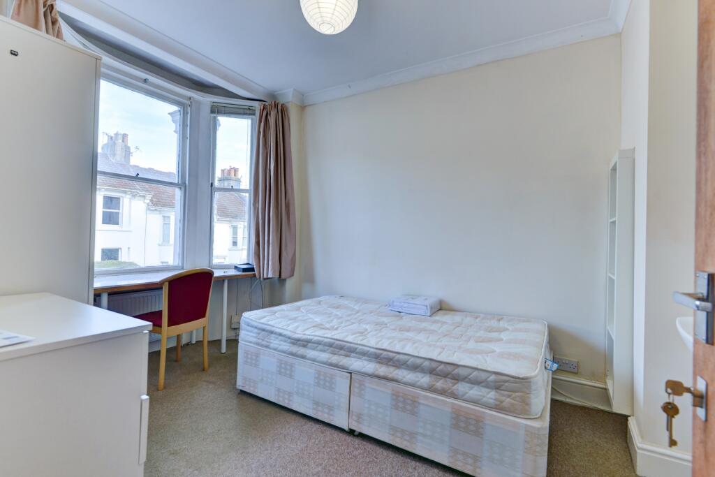 A bright single bedroom featuring a large bay w...