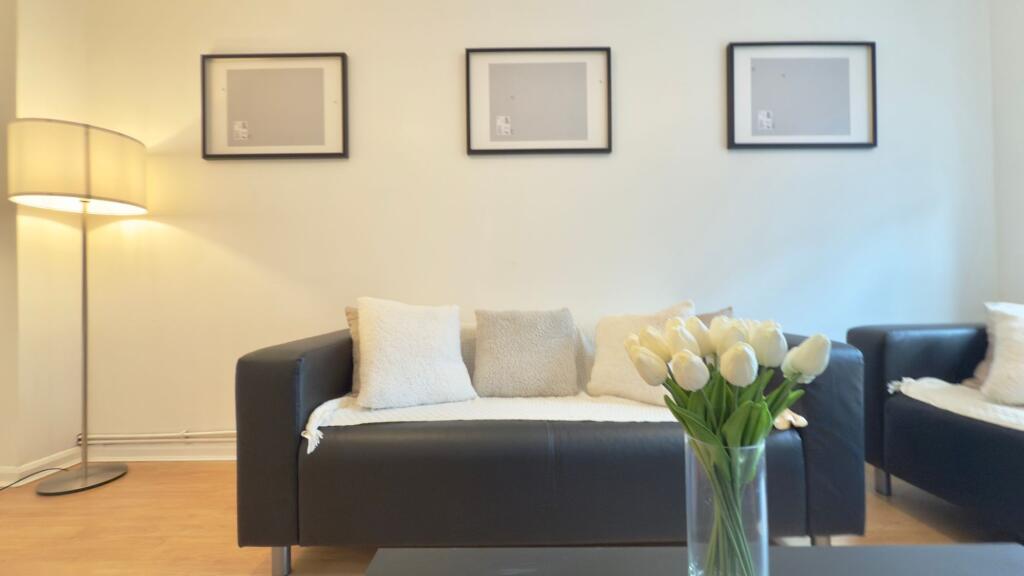 Bright, modern living room with a black leather...