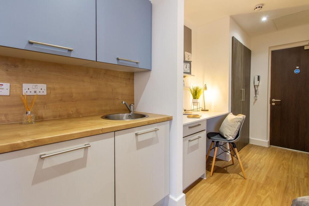 A modern, compact kitchen area featuring clean ...