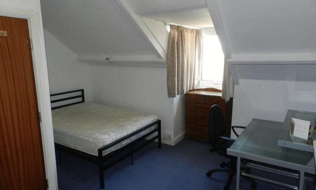 A cozy single bedroom with a neatly made bed, a...