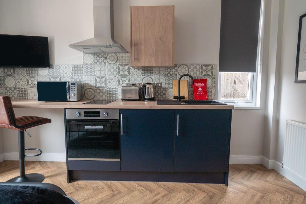 Modern kitchen with stylish blue cabinetry, a b...