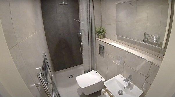 Modern, tiled bathroom with a wall-hung toilet,...