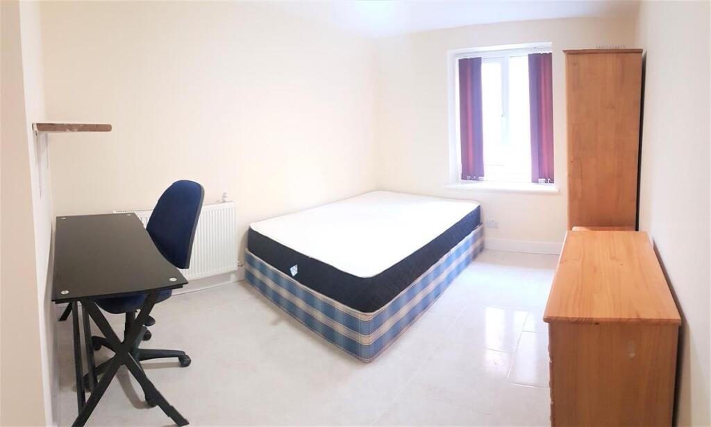 Bright, simply furnished bedroom with a double ...