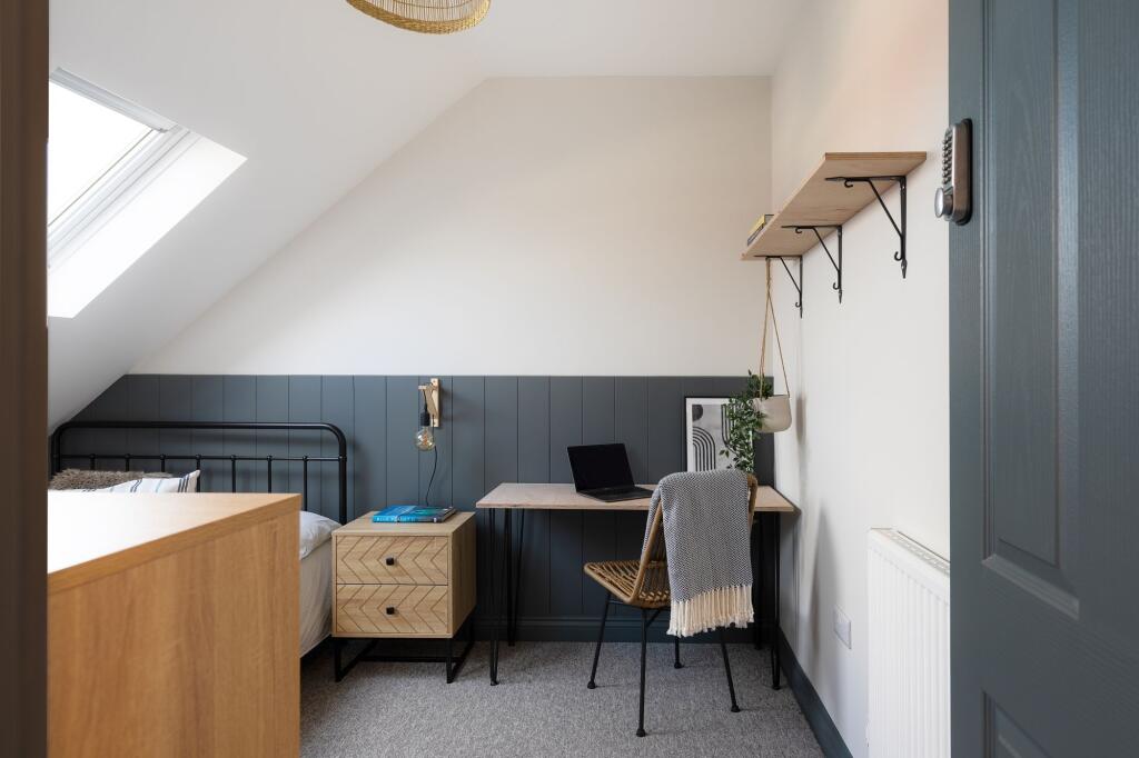 Bright, stylish bedroom with sloped skylight, c...