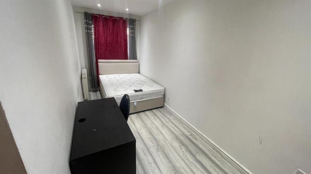 Long narrow bedroom with a bed at the end, neat...