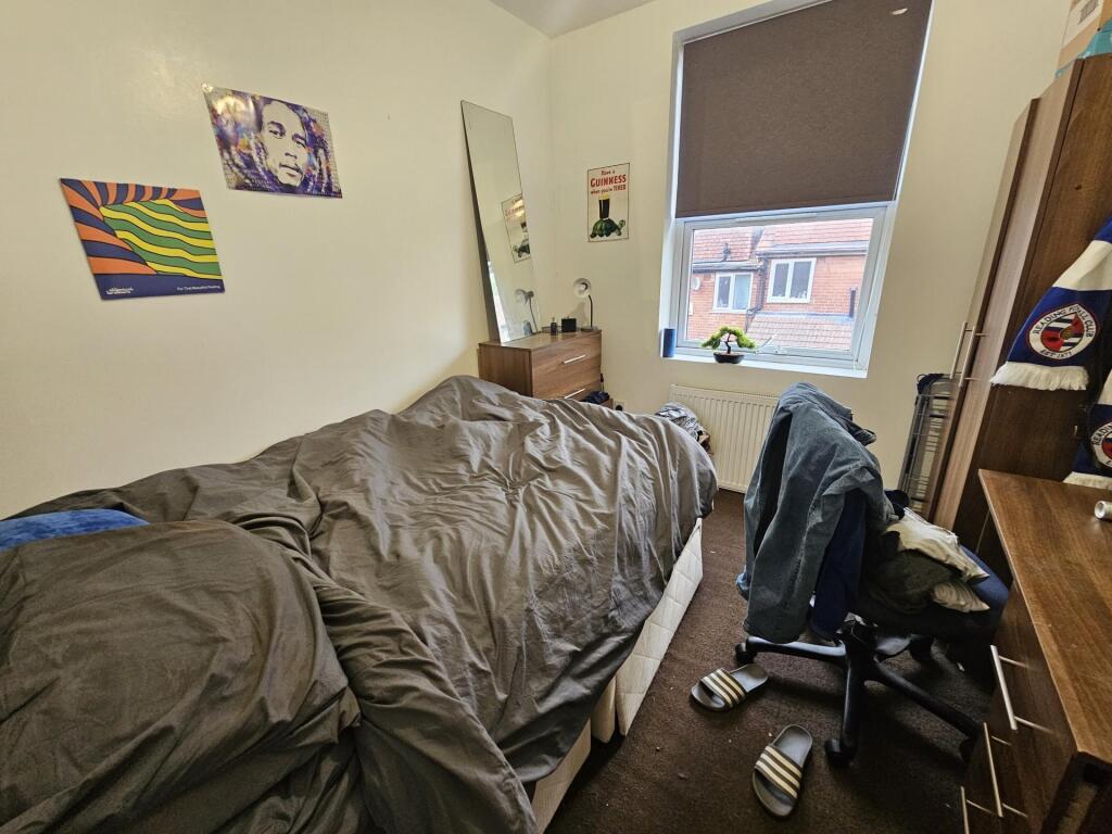 A cozy, modest bedroom with a single bed, a des...