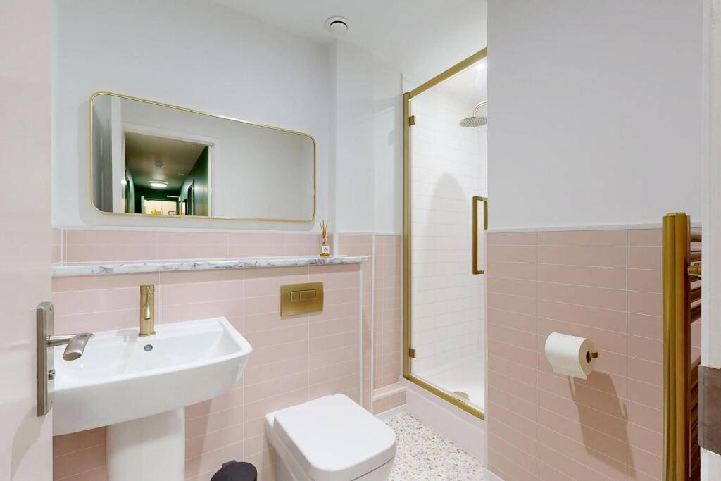 Bright, modern bathroom with pink tiled half-wa...