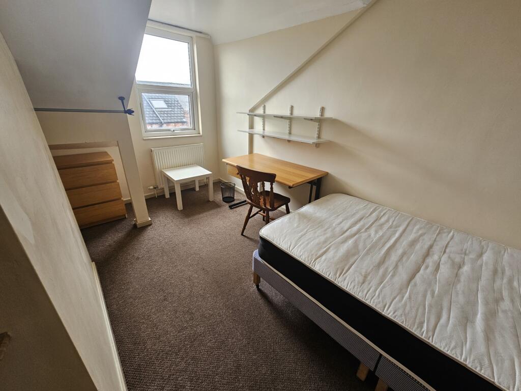 A cozy single bedroom featuring a neatly made b...