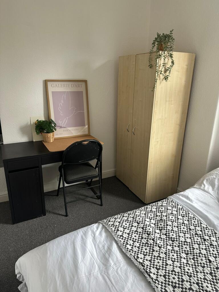 A cozy bedroom featuring a neatly made bed with...