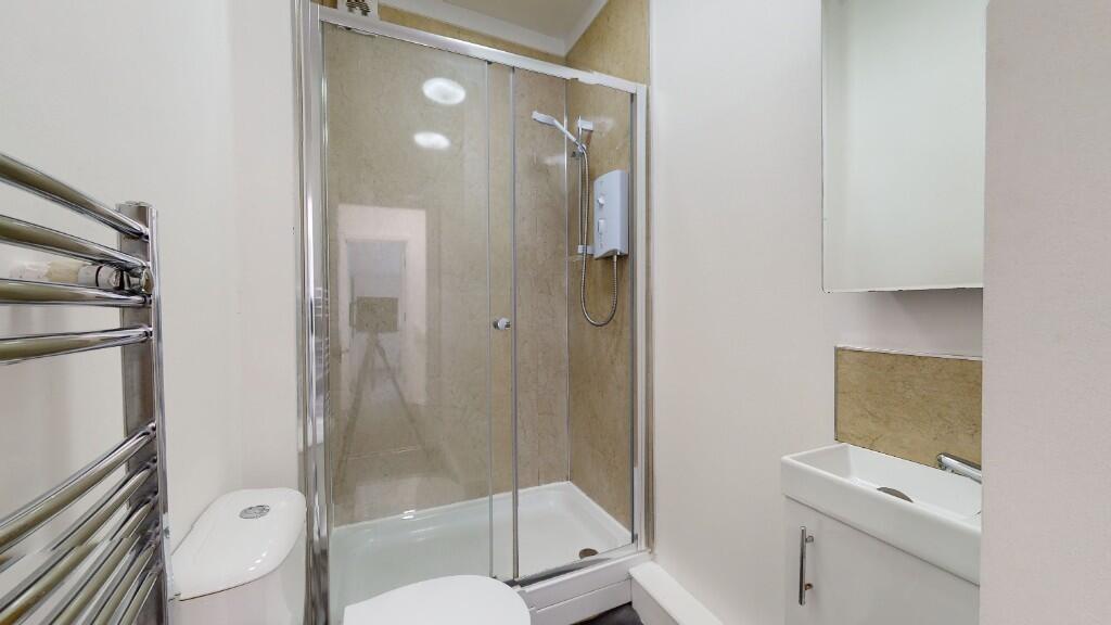 Modern bathroom suite featuring a glass-enclose...