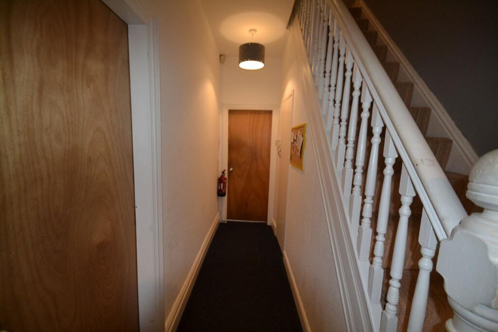 A narrow hallway with white walls and a beige c...