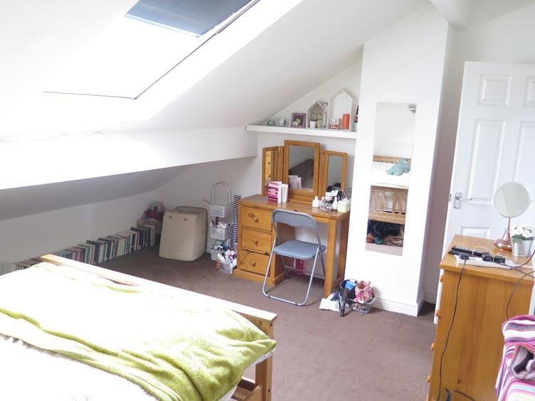 A cozy master bedroom with a sloped ceiling and...