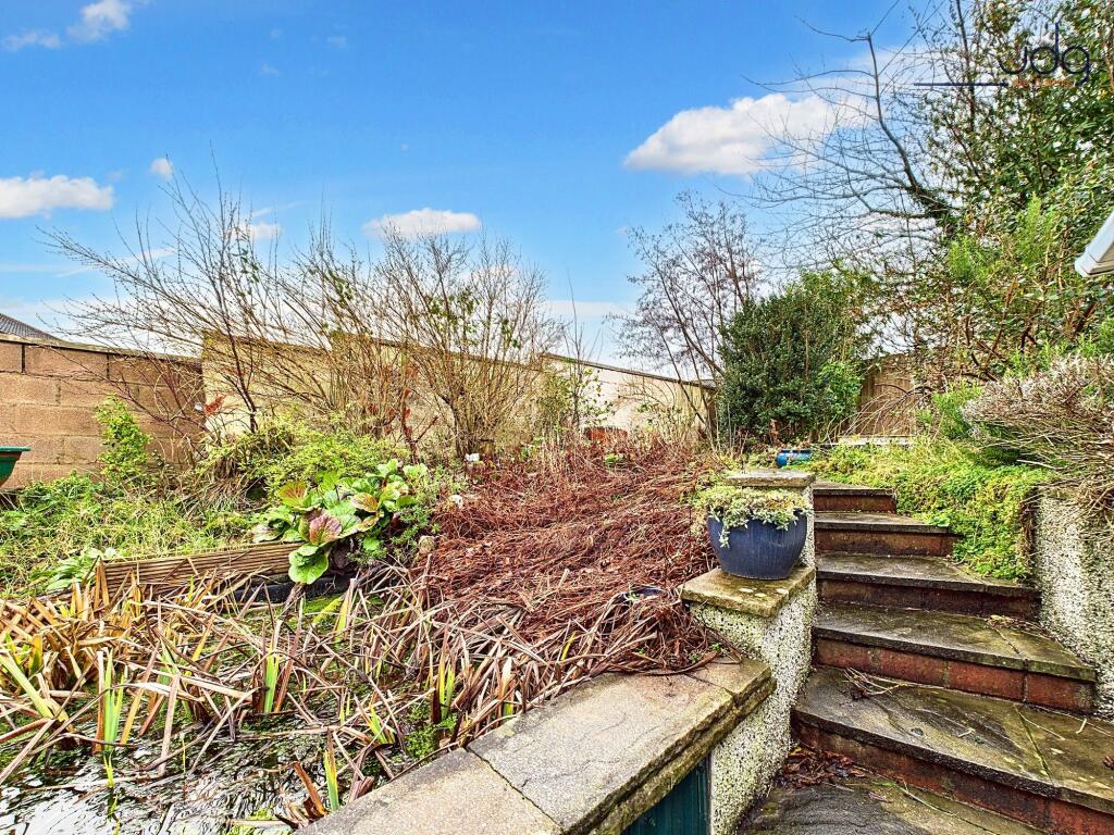 Tiered rear garden with pond and seating area