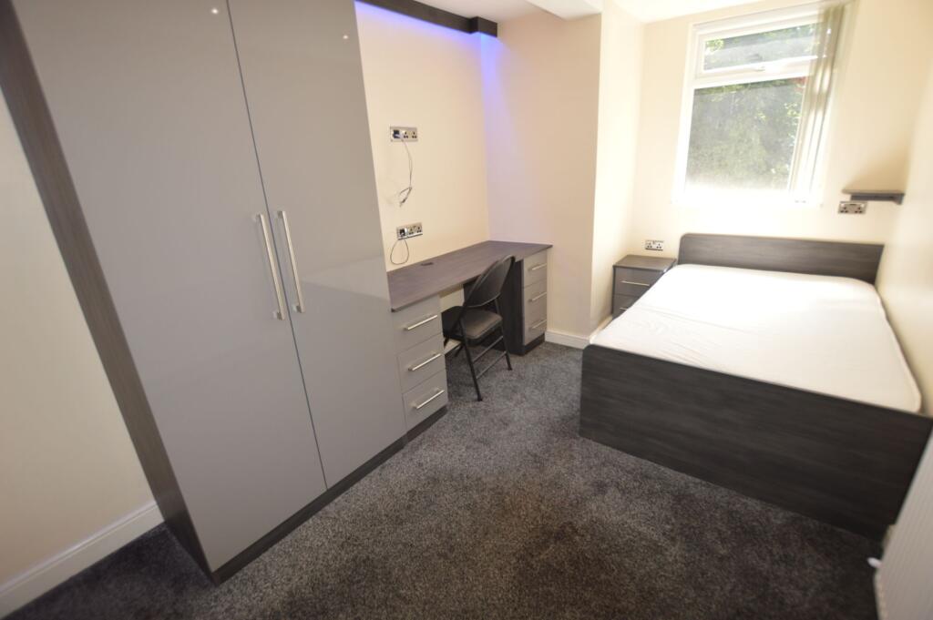 A tidy and bright student bedroom featuring a c...