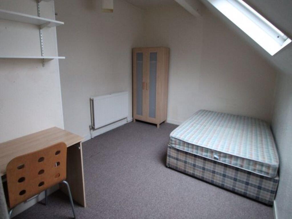 A neat single bedroom featuring a cozy bed unde...