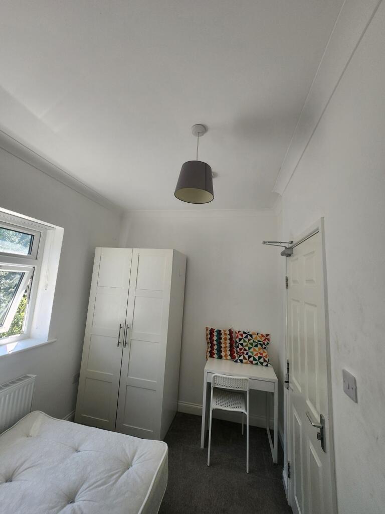 A tidy and well-lit student bedroom featuring a...