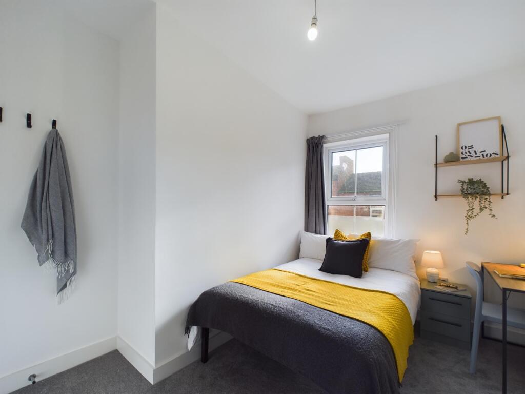 A bright and welcoming bedroom featuring a comf...