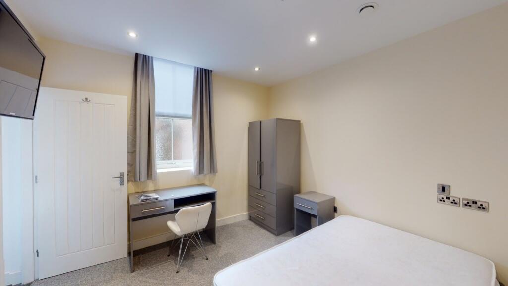 A neat and well-lit bedroom featuring a clean s...