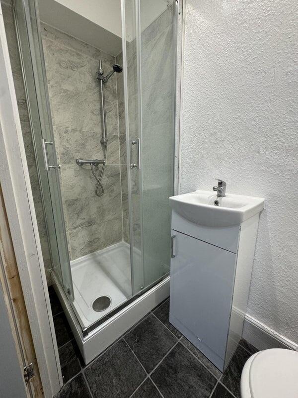 A modern bathroom featuring a clean glass-enclo...