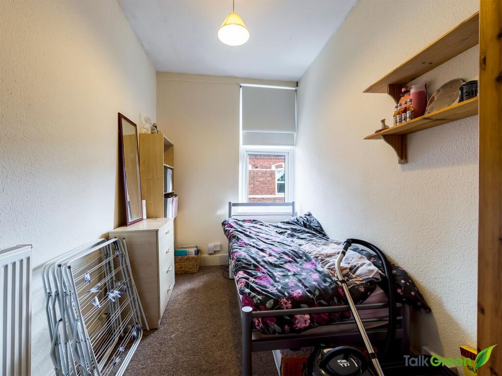 A compact single bedroom with a small bed, stra...