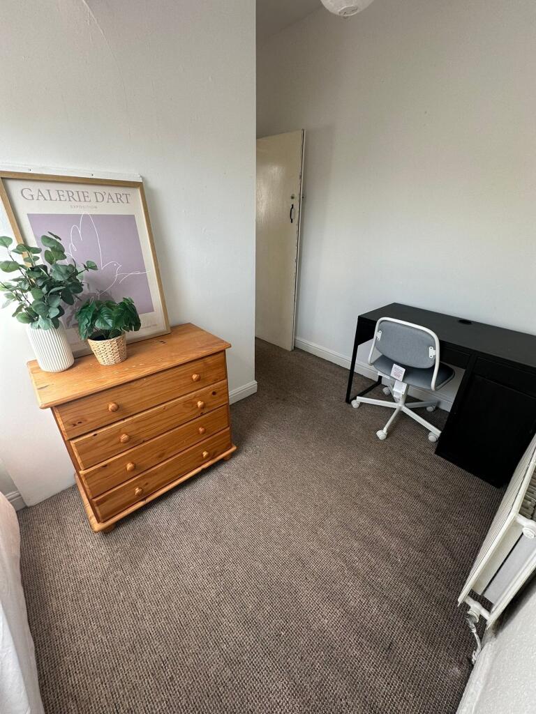 A cozy single bedroom featuring a wooden dresse...