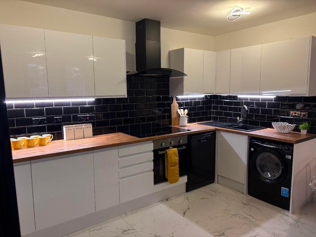 A modern kitchen featuring sleek white cabinetr...