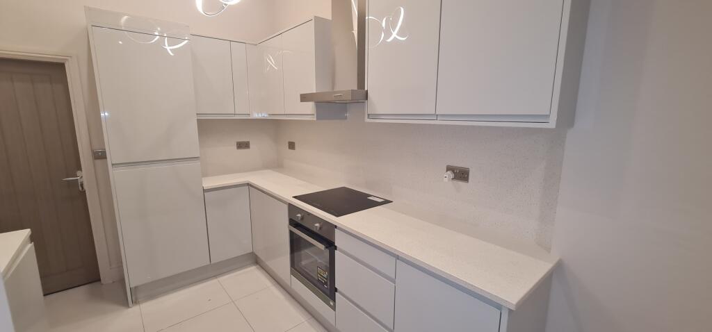 A modern, clean kitchen featuring white cabinet...