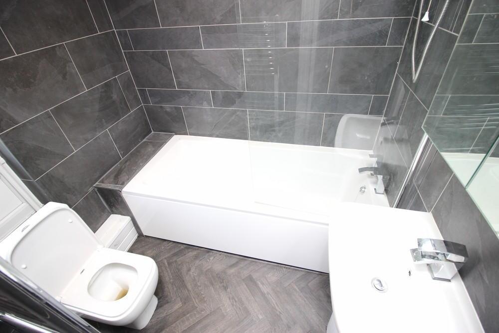 A modern bathroom featuring a white bathtub wit...