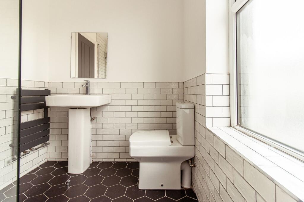Bright, modern bathroom with geometric black fl...