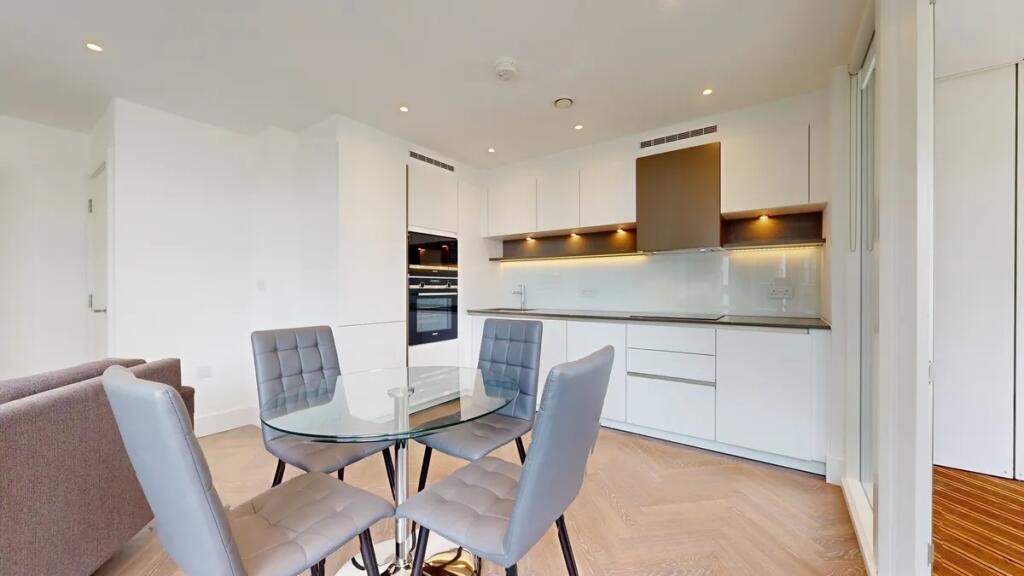A modern, sleek kitchen featuring white cabinet...