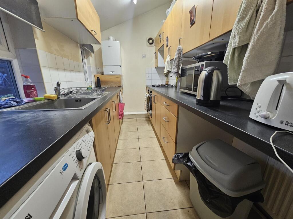 Narrow galley kitchen with black countertops, l...