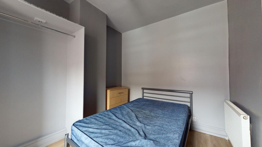 A tidy bedroom featuring a simple bed frame wit...