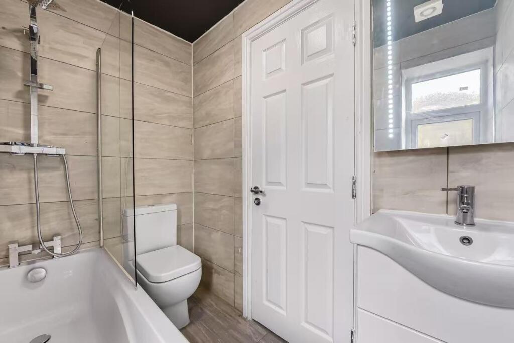 A modern, clean bathroom featuring a bathtub wi...