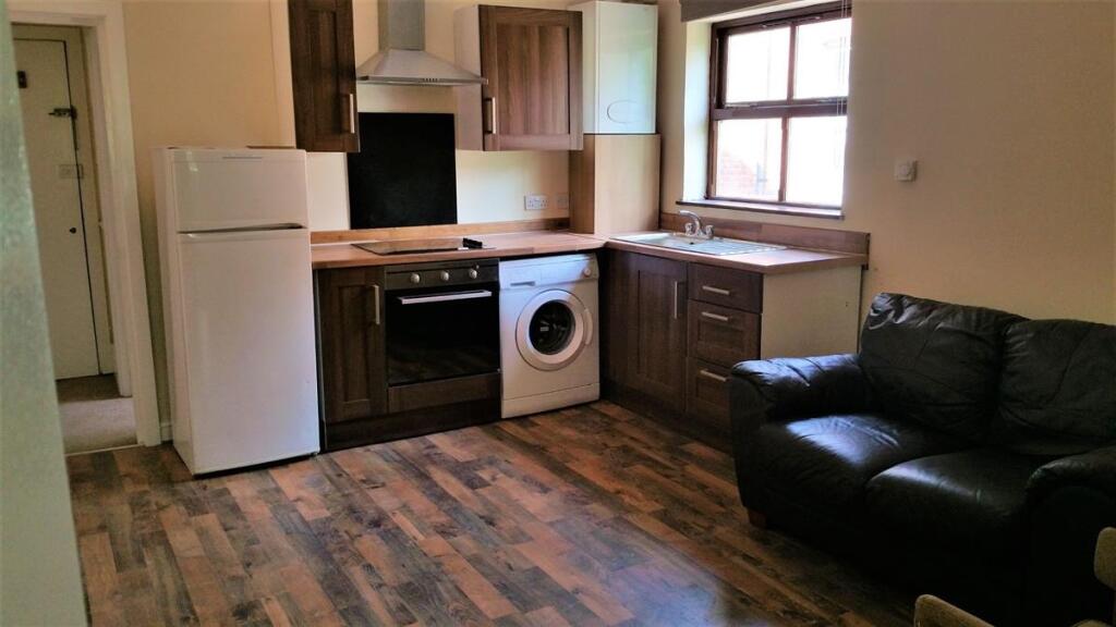 Open-plan kitchen area with fitted cabinets, in...
