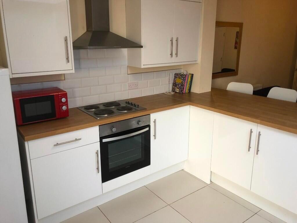 A modern kitchen featuring white cabinetry, a b...