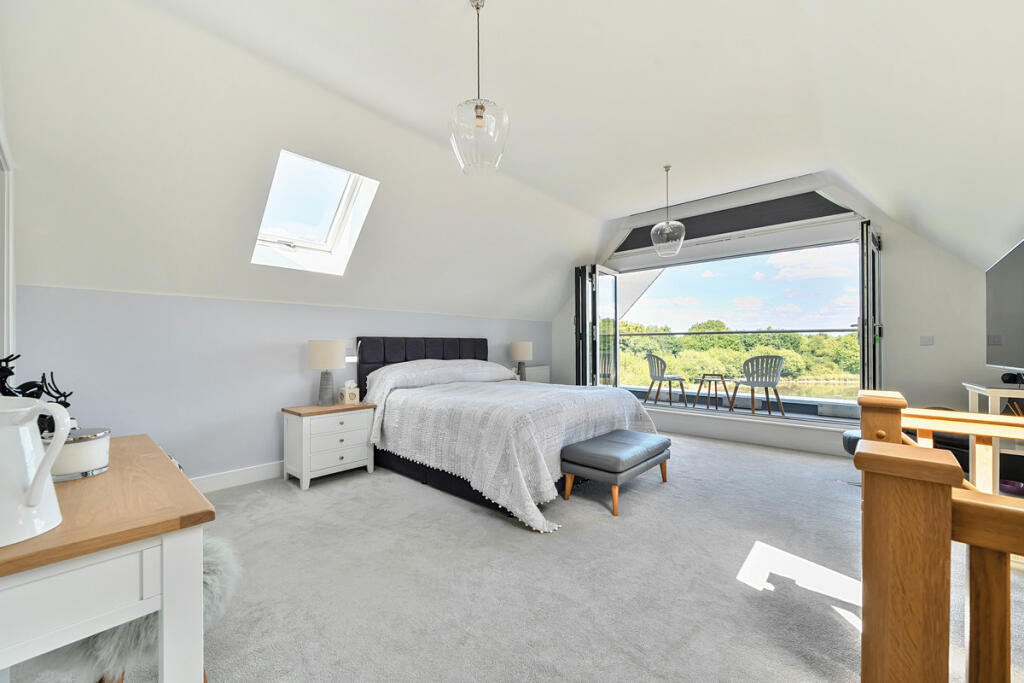 Master Bedroom with vaulted ceiling and bi-fold doors opening onto balcony with views over the lake