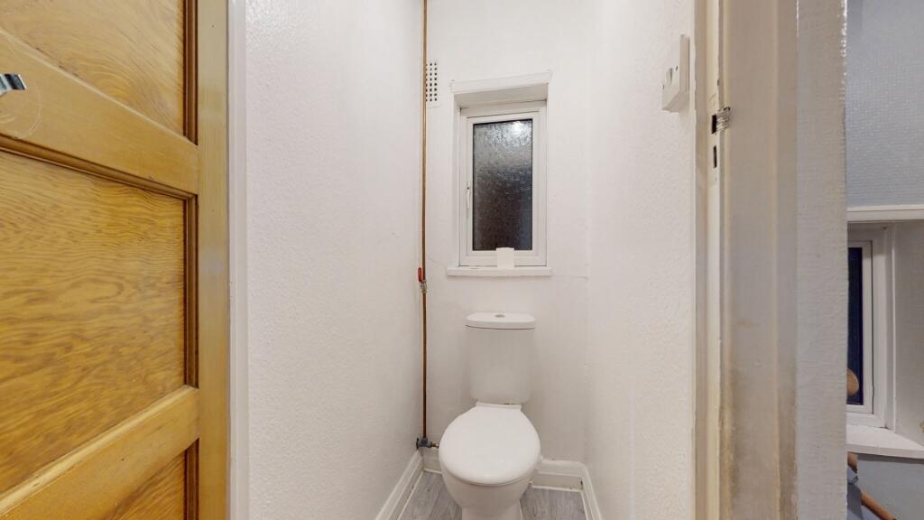 A clean and simple single toilet room featuring...