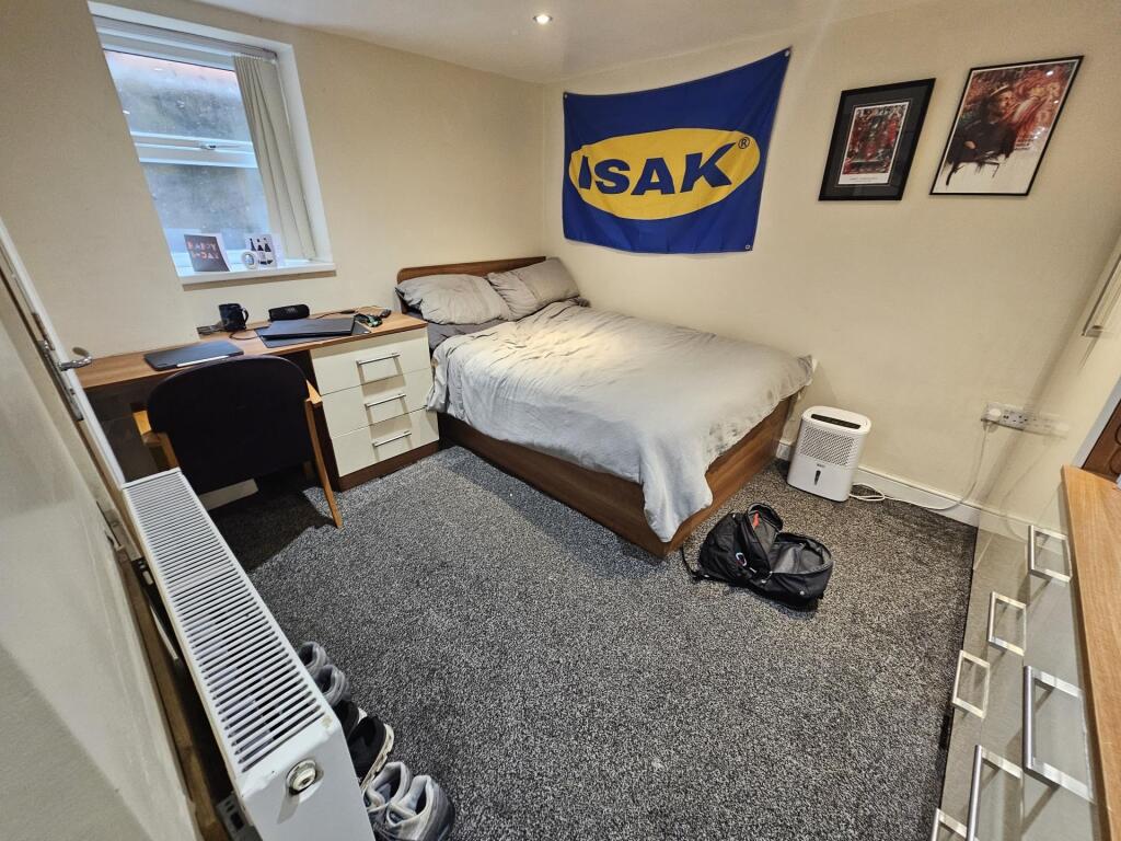 A tidy bedroom featuring a double bed, a desk, ...