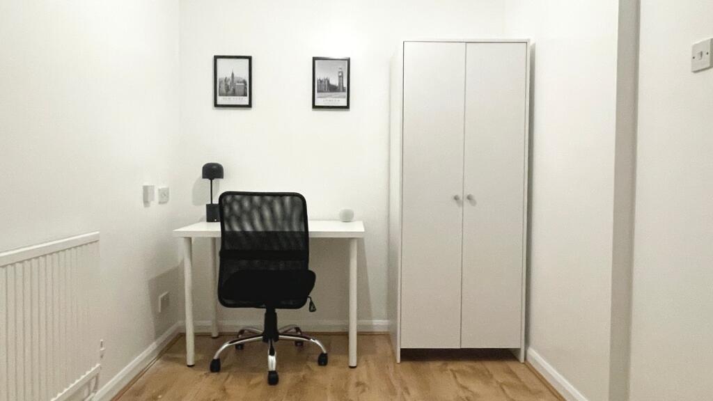 A cozy double bedroom featuring a well-lit work...