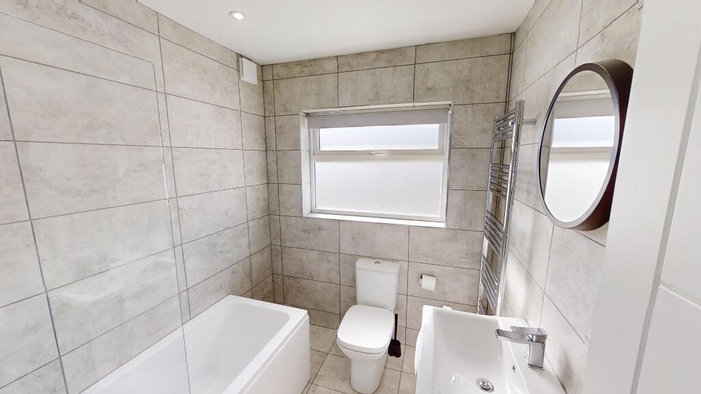 A bright and modern bathroom suite featuring a ...