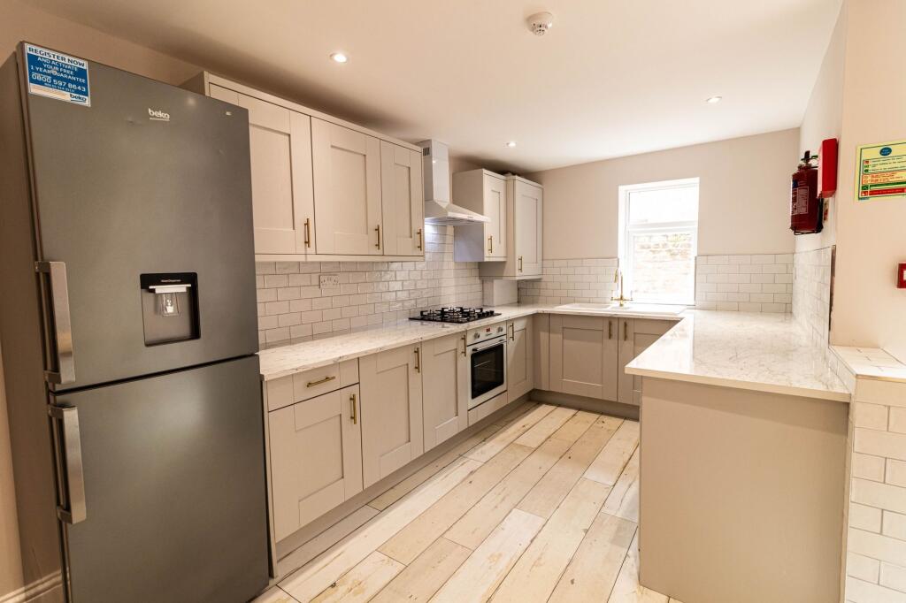 Modern kitchen with cream cabinetry, marble cou...