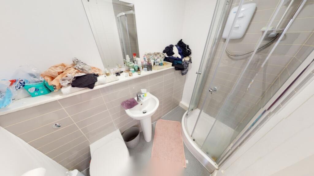 A compact bathroom featuring a modern shower an...